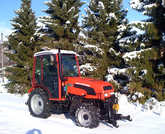 Dexheimer 509 im Wintereinsatz Traktor mit Schneeketten im verschneiten Waldgebiet